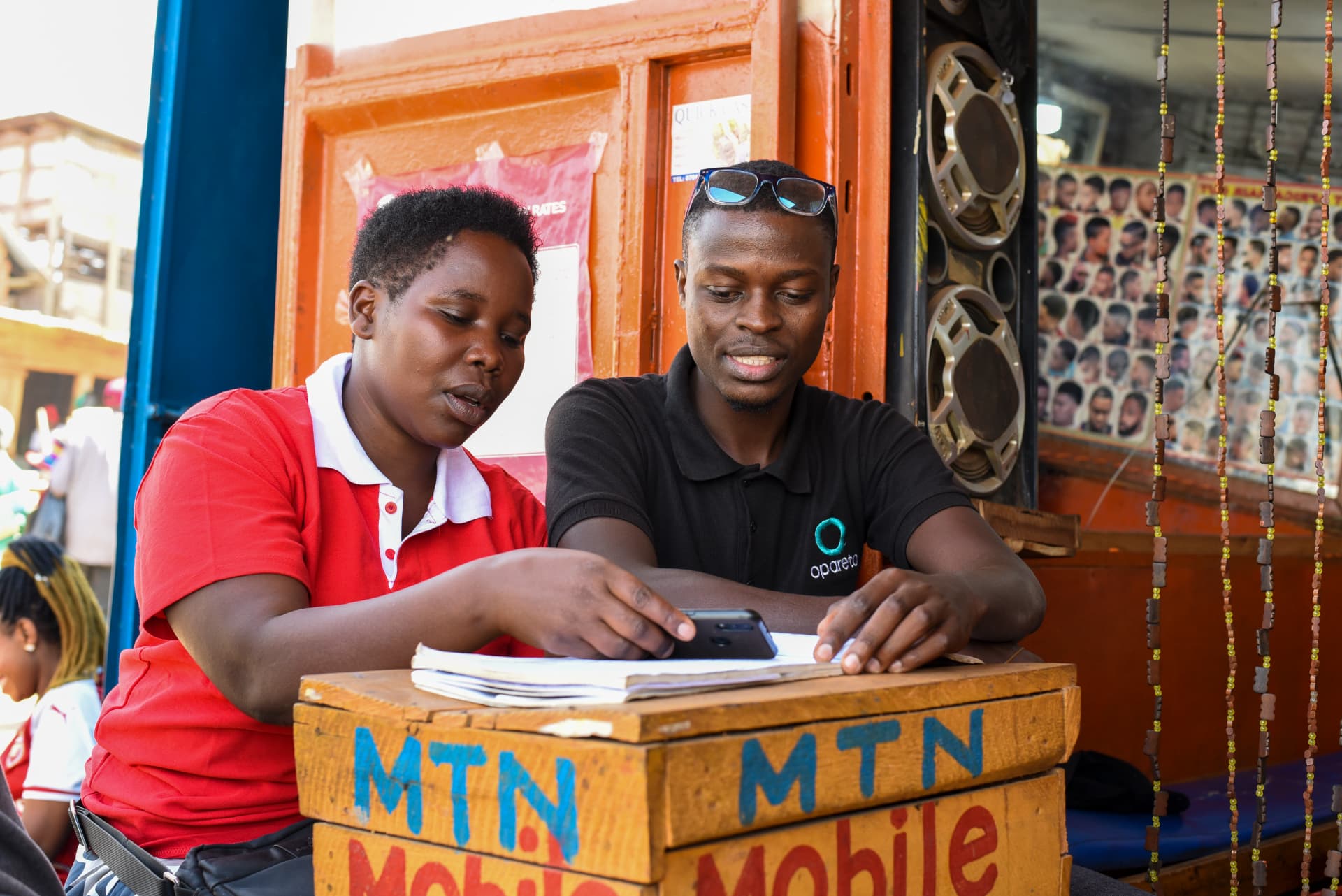 Opareta field agent supporting a mobile money agent at an MTN kiosk