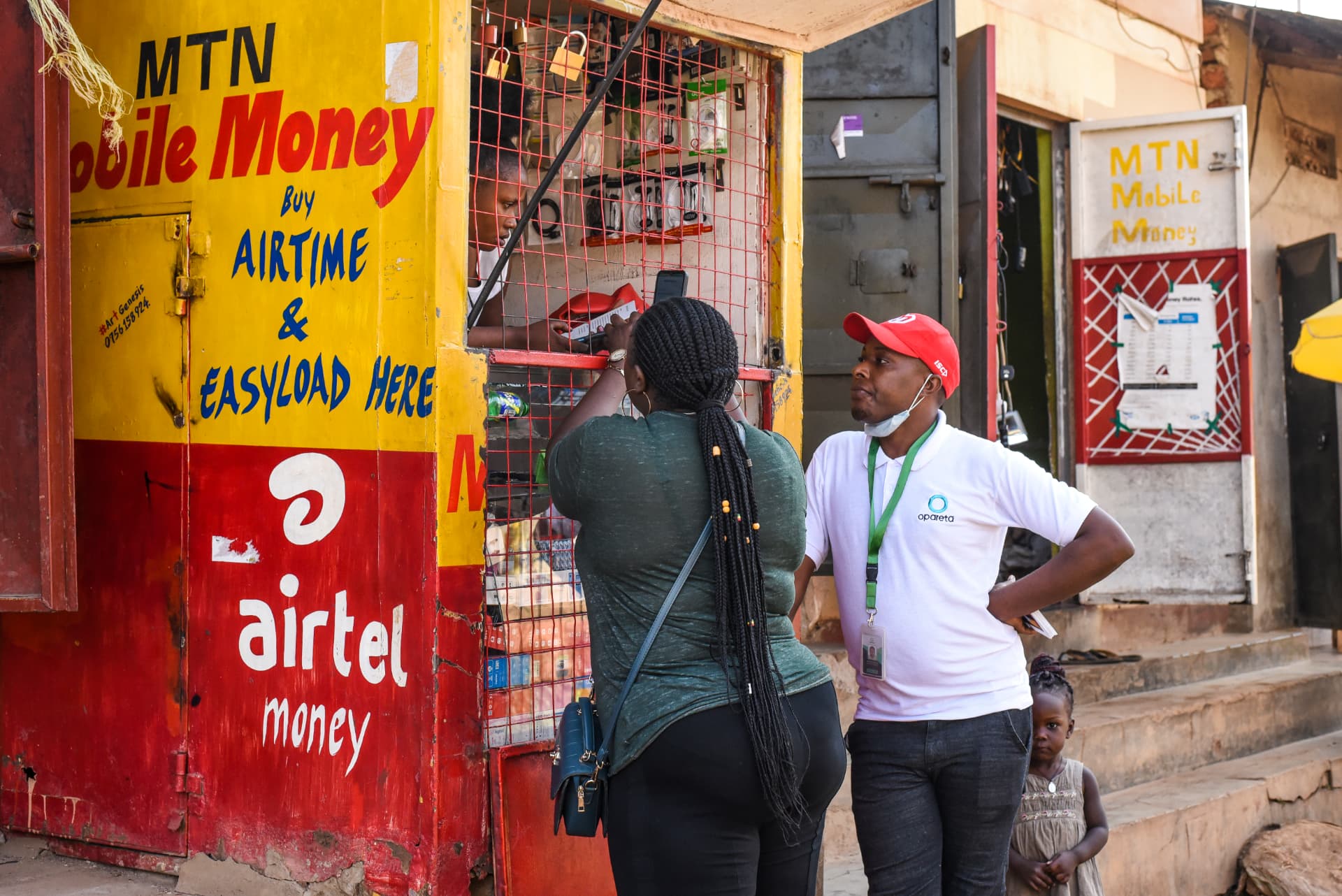 Opareta field agent with a mobile money agent at a kiosk